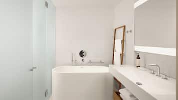 A modern bathroom with a freestanding bathtub, a large mirror, and a vanity with a sink.
