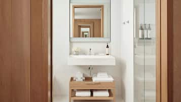 A bathroom with a wooden vanity, a white sink, and a mirror.