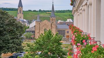 A town with a church, a building with a clock tower, and a vineyard in the background.
