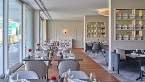 Ein Restaurant mit mehreren Tischen, einem großen Fenster und einer Wand mit einer Plattenausstellung.