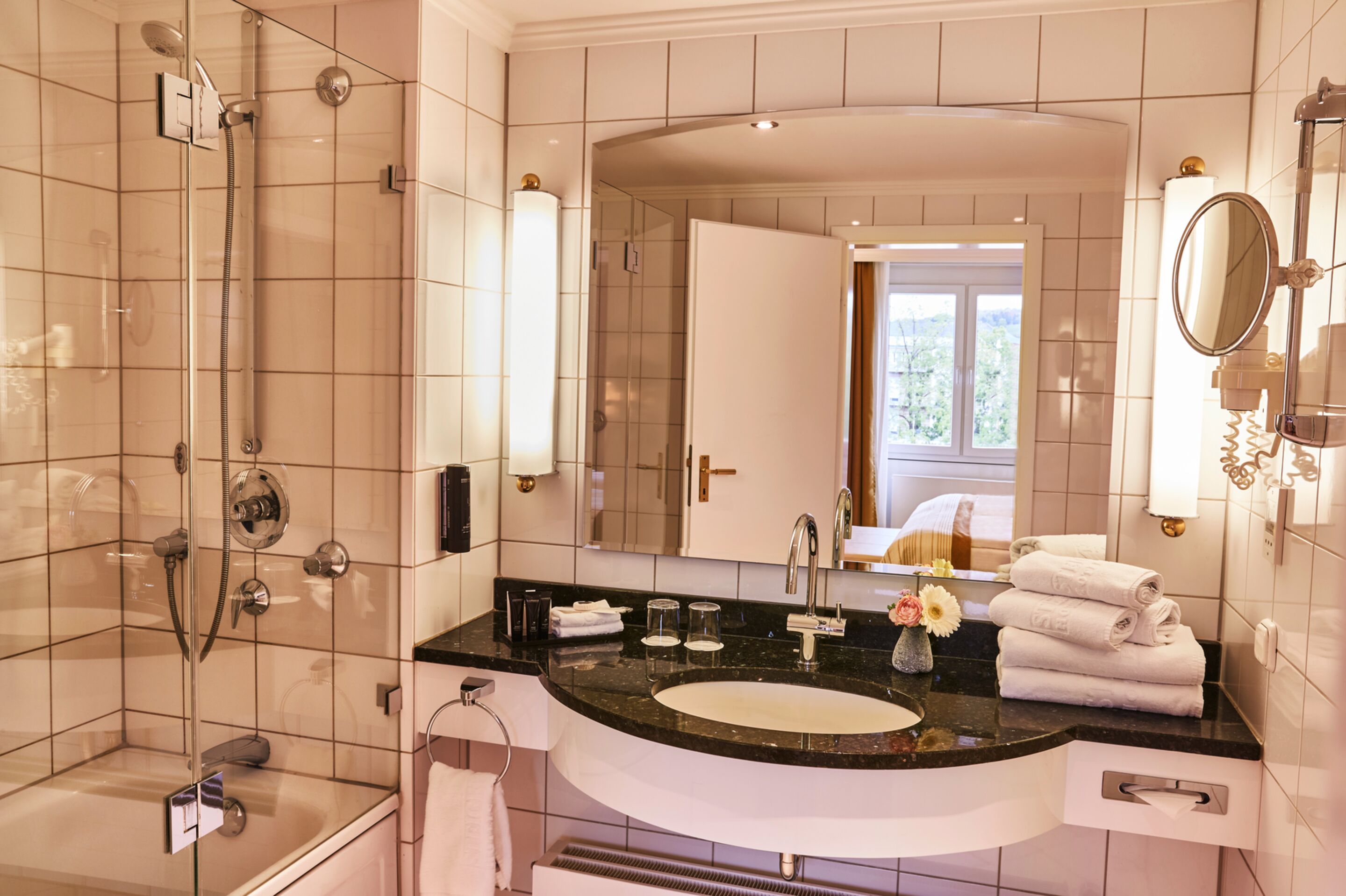 A modern bathroom with a glass-enclosed shower, a large vanity with a sink, and a mirror.