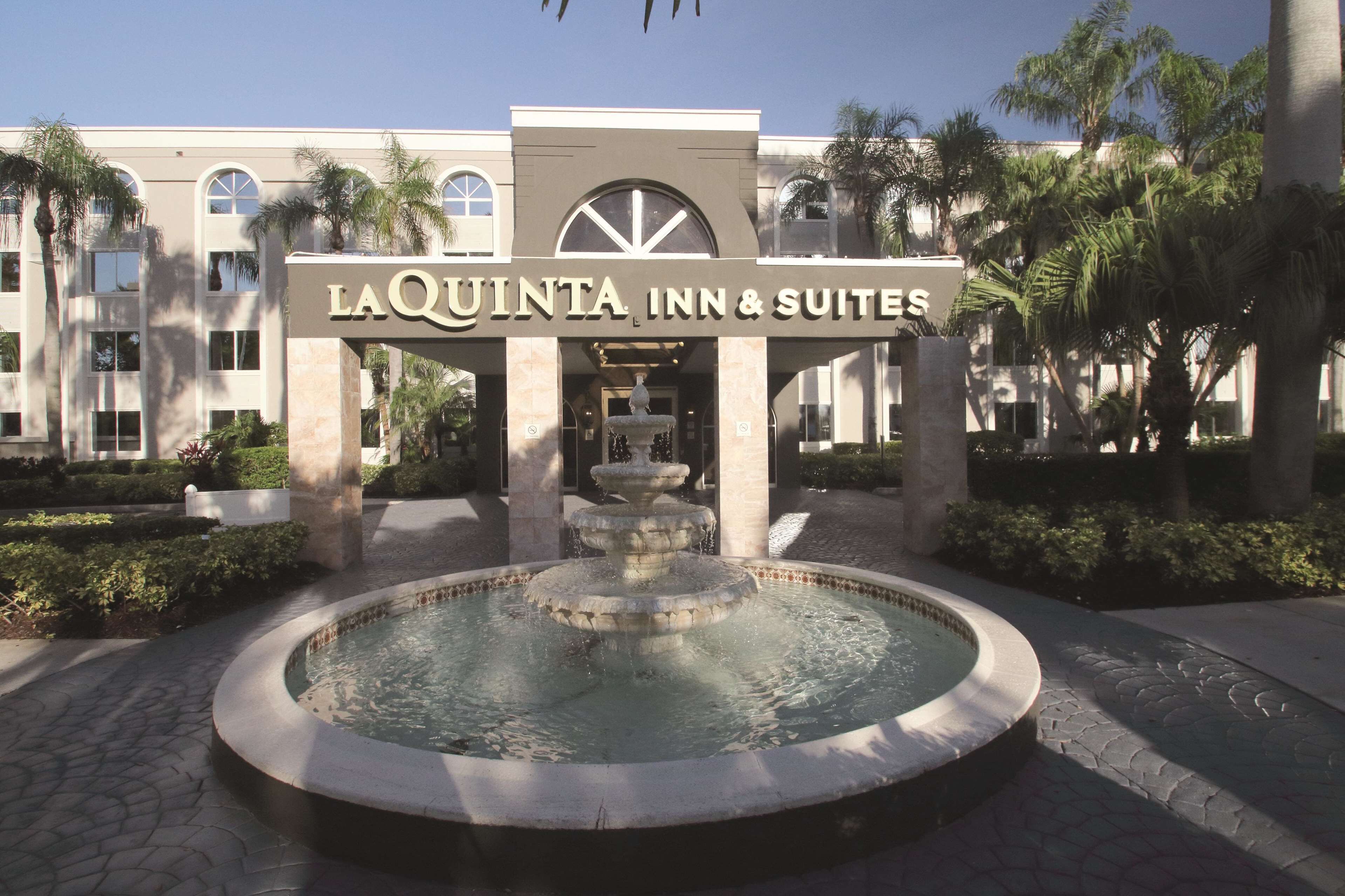 La entrada del La Quinta Inn & Suites, con una fuente central y palmeras.