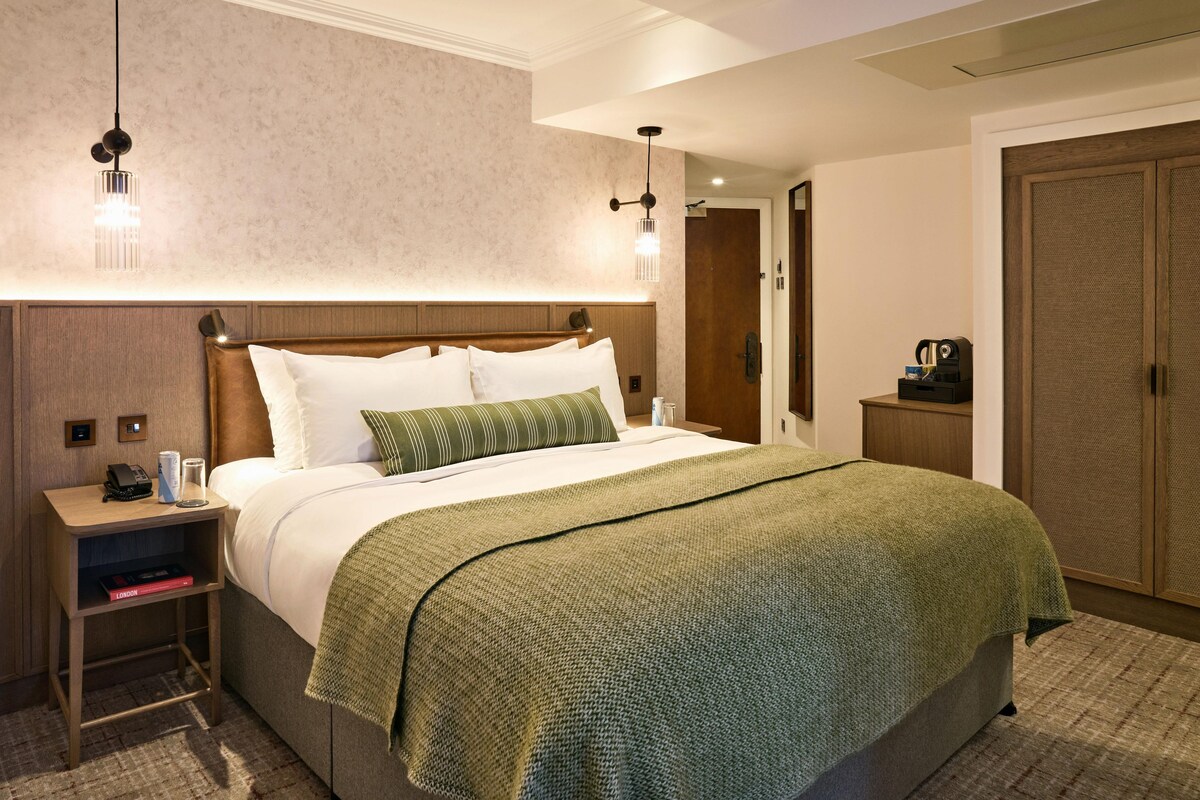 Une chambre d’hôtel avec un grand lit, des tables de chevet, une armoire et une porte.