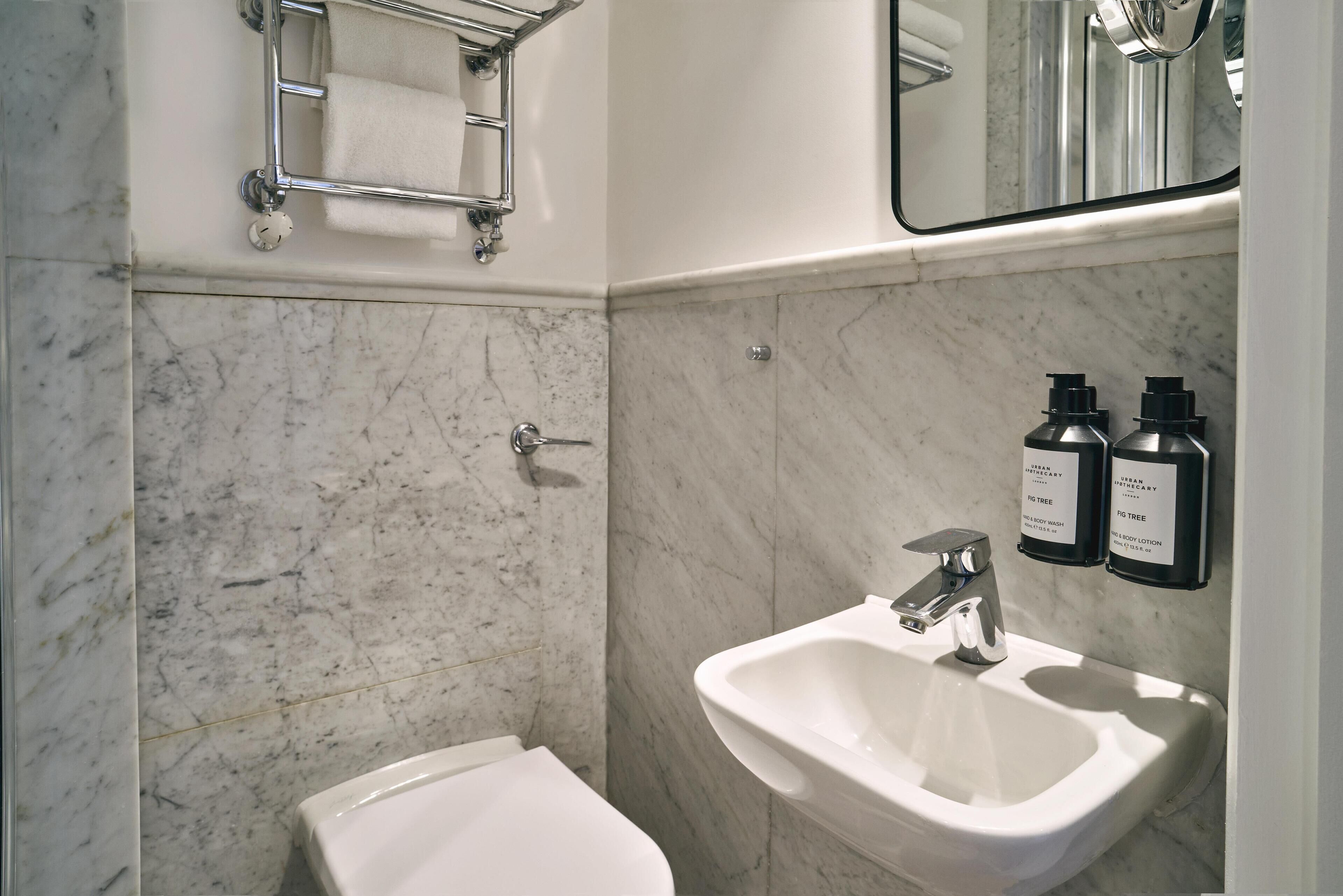 A bathroom with a white toilet, a sink, and a towel rack.