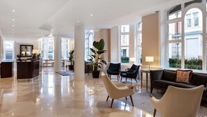 Un vestíbulo amplio con mostrador de recepción, zona de estar y ventanas grandes que ofrecen vistas de la ciudad.