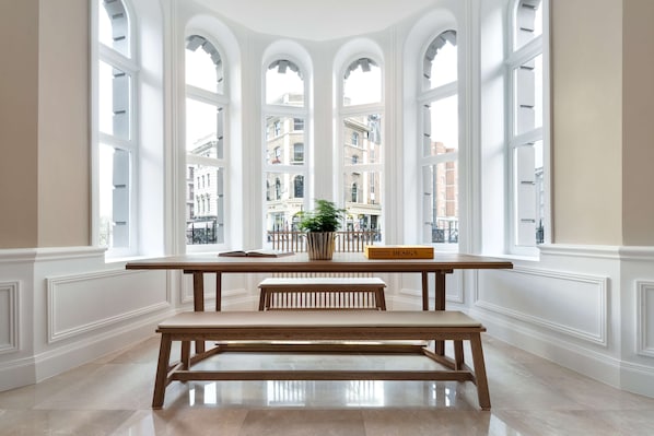 A room with a large window, a wooden bench, a small table, and a potted plant. - Radisson Blu Hotel, London Tottenham Court Road (London)