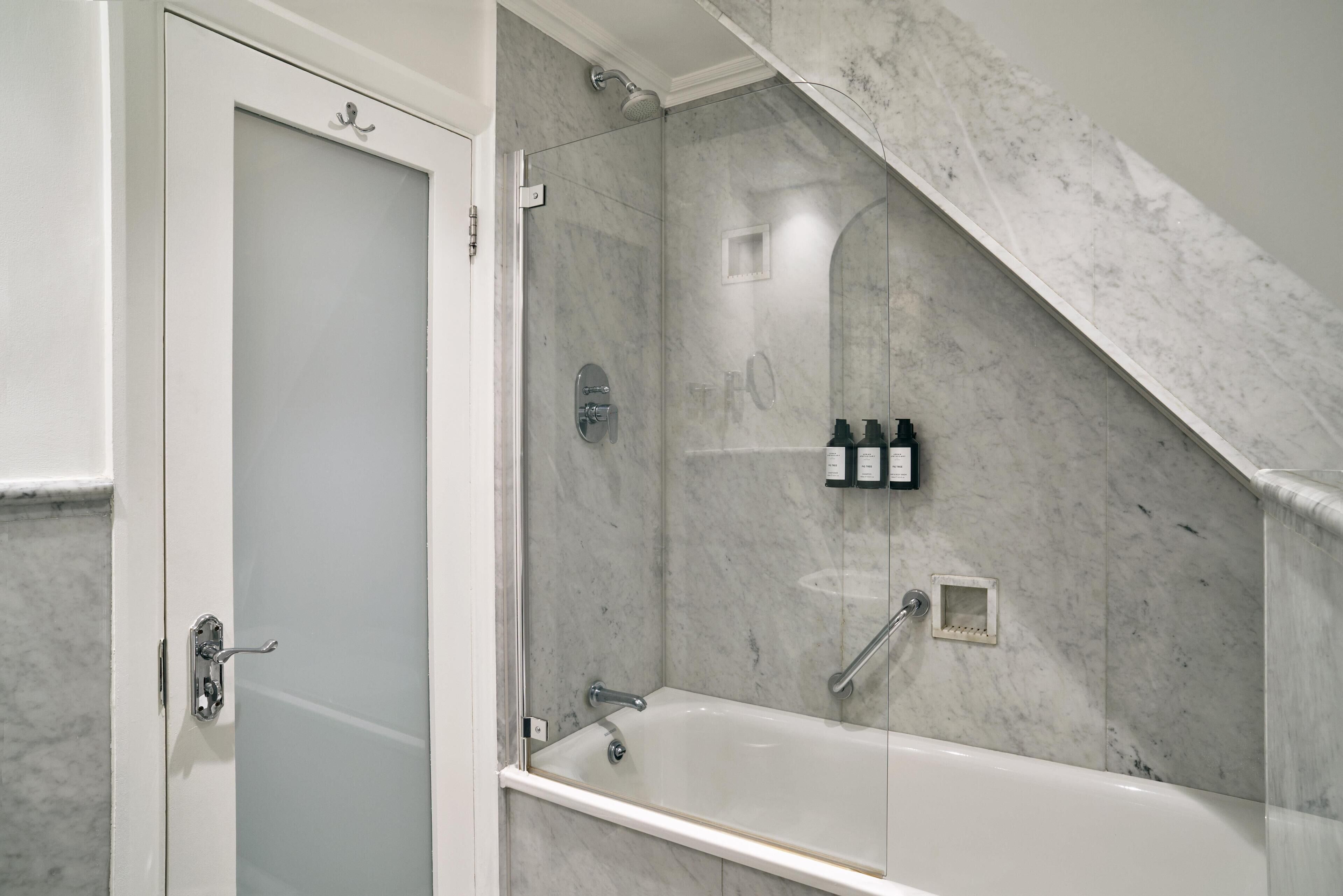 A bathroom with a shower, a bathtub, and a door.