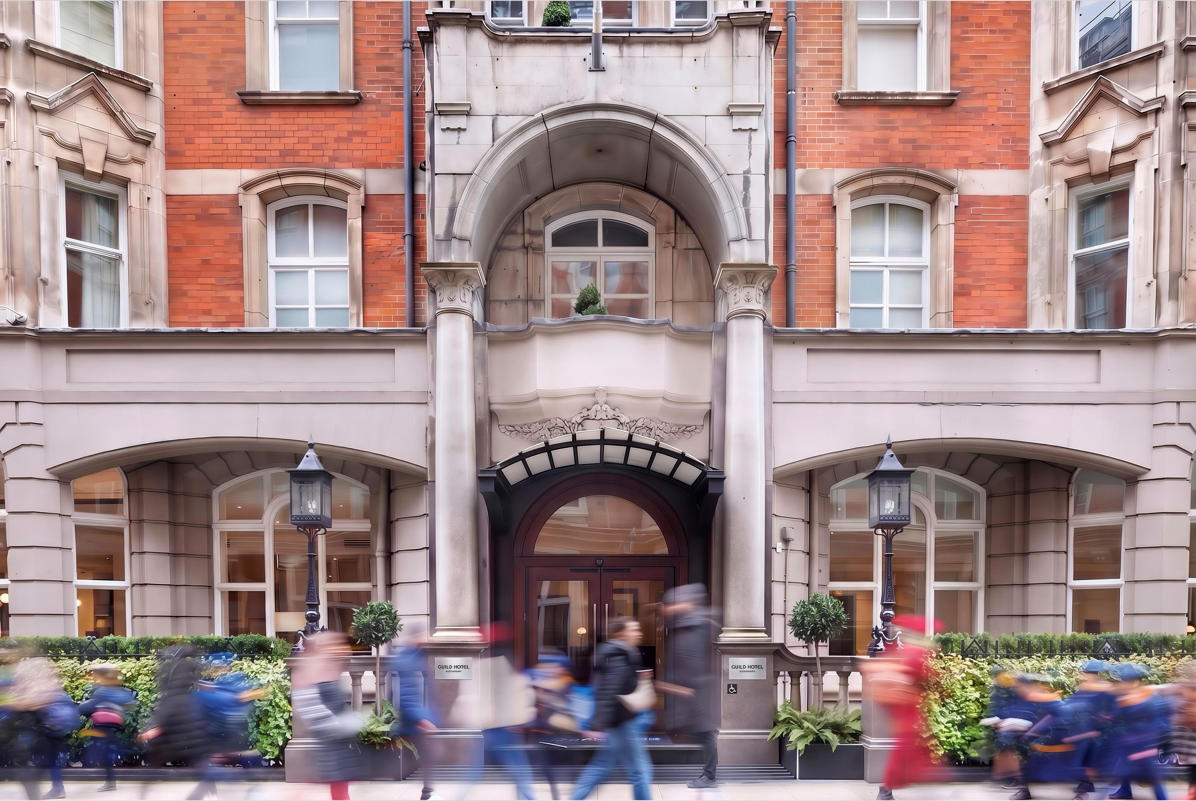 A building with a central entrance, multiple windows, and a sign indicating it's a hotel.