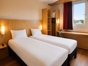 A hotel room with two beds, a desk, a chair, a wardrobe, and a window with a view. - ibis Paris Porte d'Italie (Gentilly)