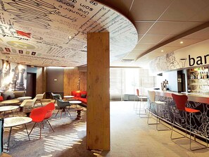 A modern bar area with a curved ceiling featuring a map design, a bar counter with stools, and a seating area with round tables and chairs. - ibis Paris Porte d'Italie (Gentilly)