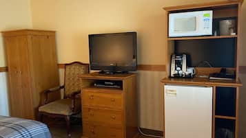 Hotelkamer met televisie, kleine koelkast, magnetron, koffiezetapparaat en kast.