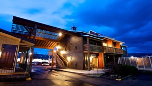 A modern two-story building with a covered entrance, outdoor seating area, and a staircase leading to the upper level. - Cousins Country Inn (The Dalles)
