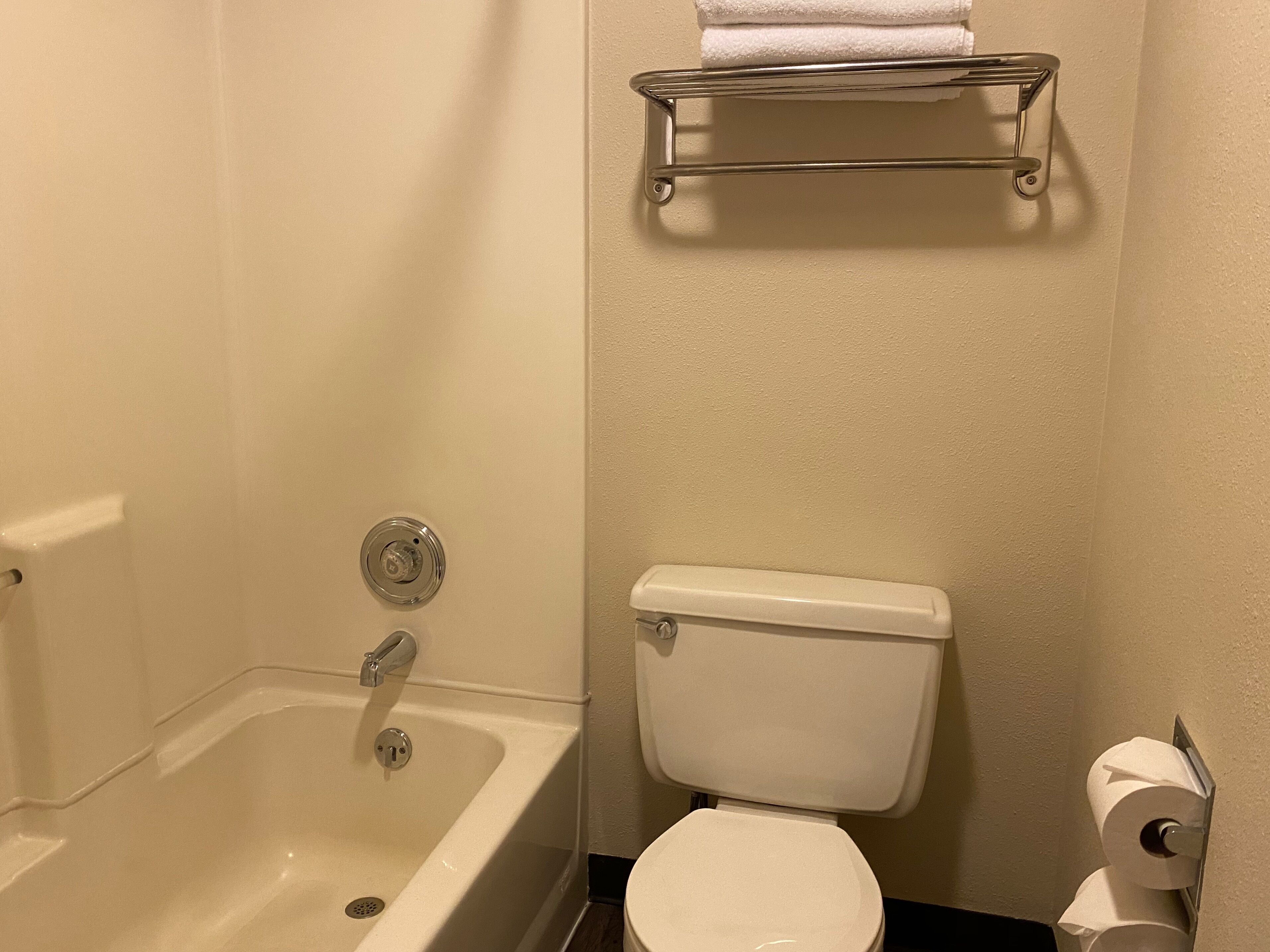 Een badkamer met een bad, toilet en een handdoekhouder.