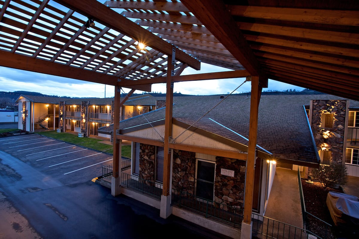 Un hotel con area esterna coperta, facciata in pietra e numerose finestre illuminate.