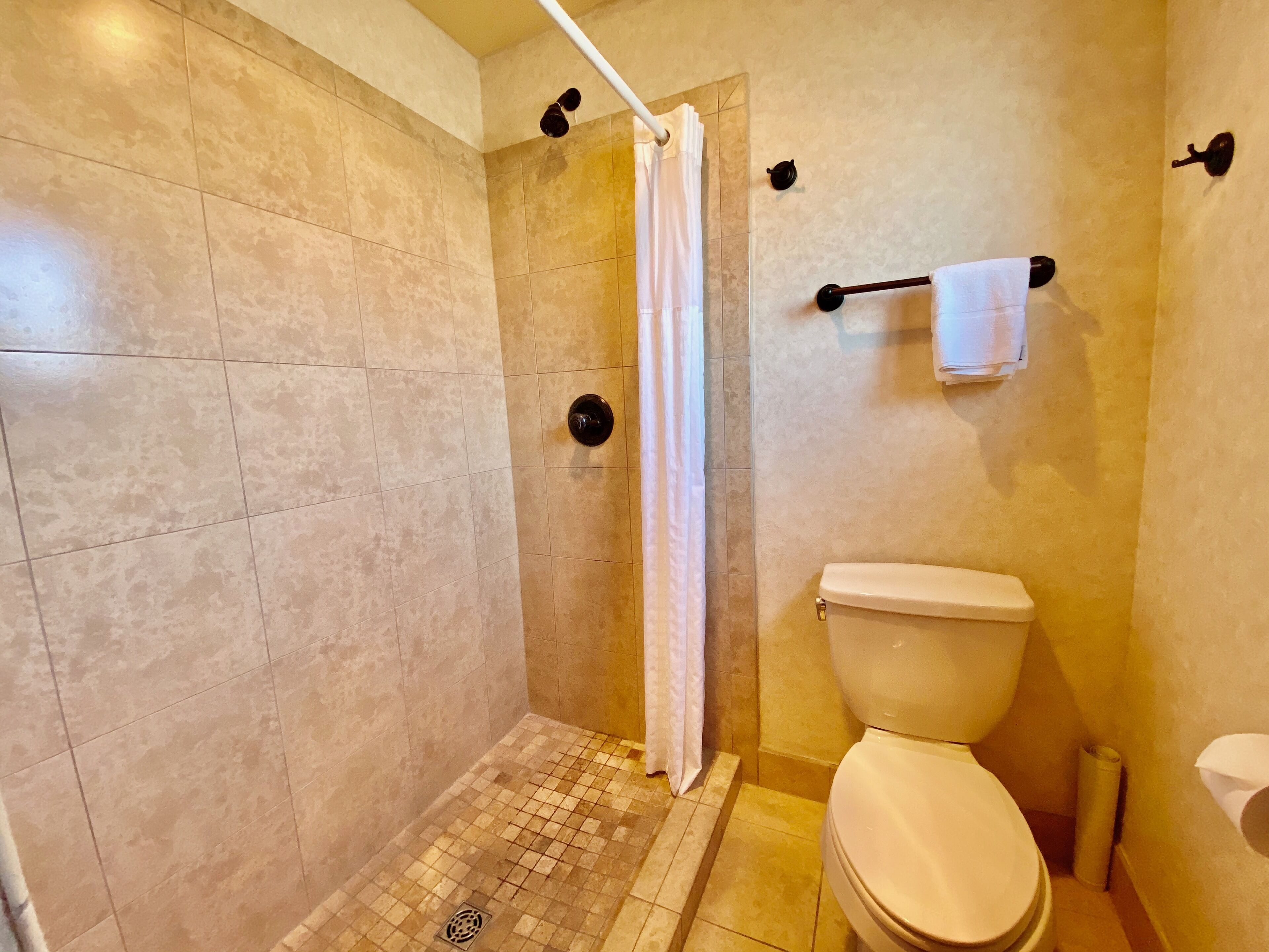 A bathroom with a shower, toilet, and a towel rack.