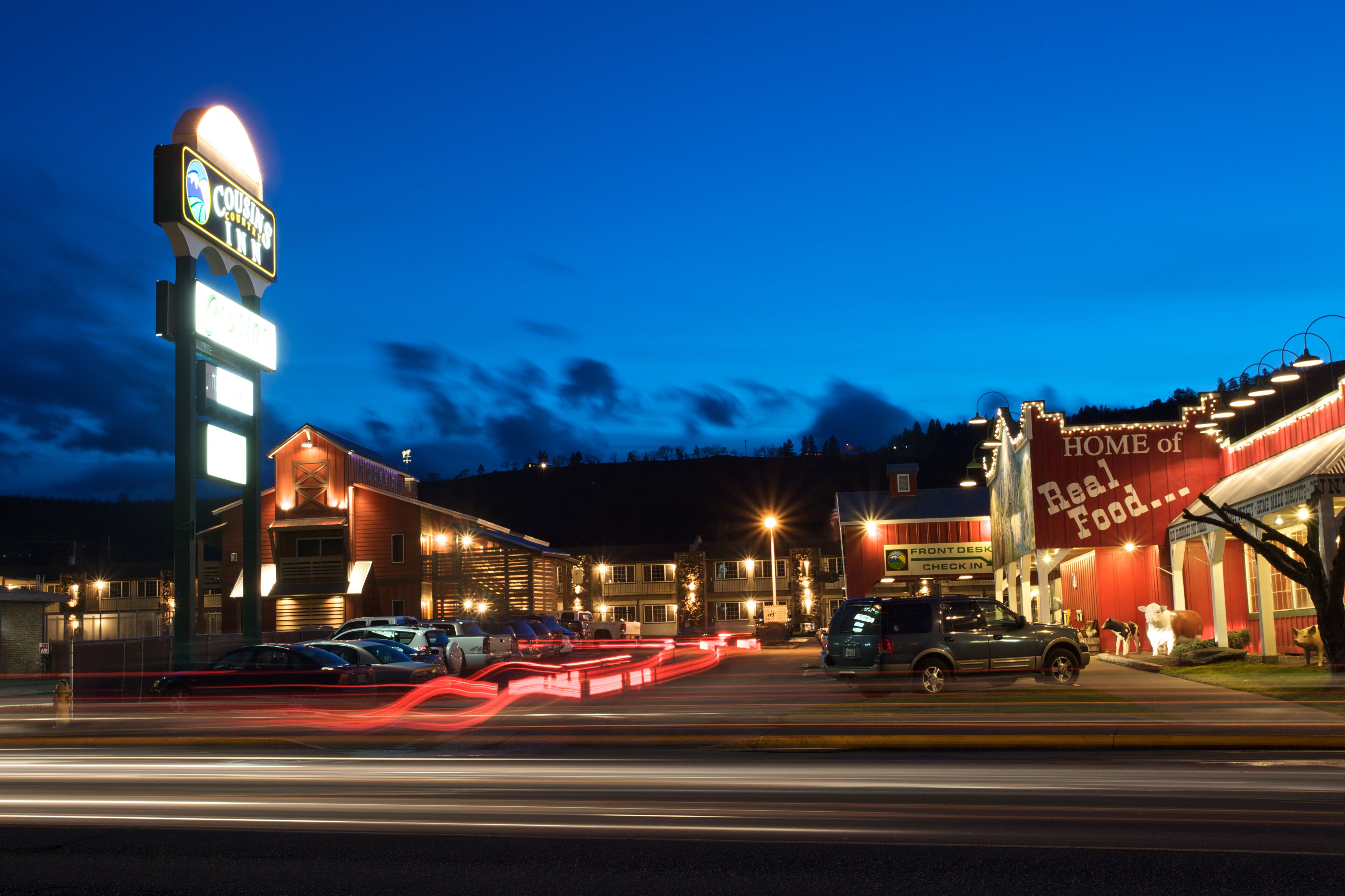 A hotel with a prominent sign, a front desk, and a building with a large sign advertising 'HOME of Real Food...'.
