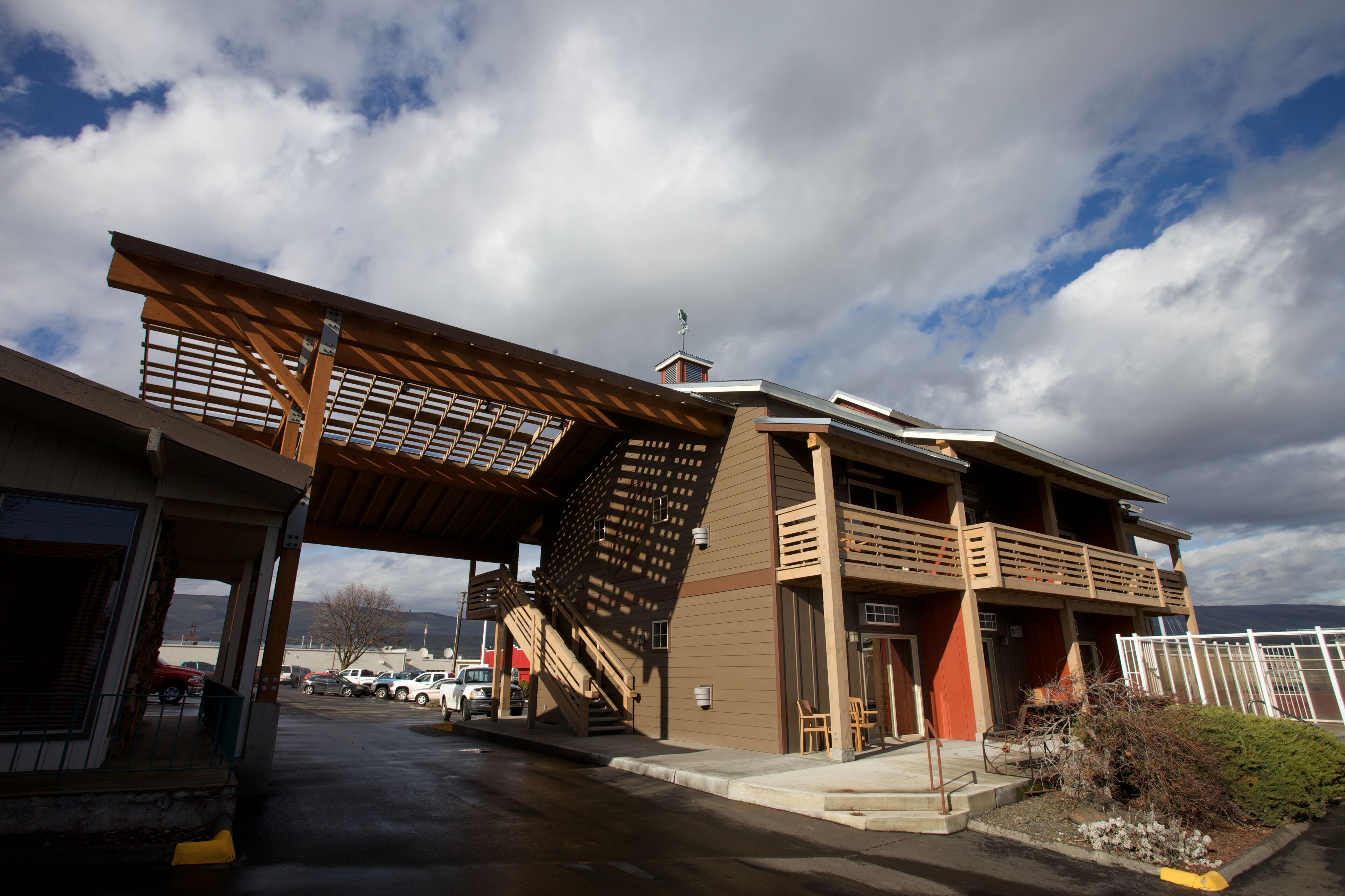 A modern building with a covered entrance, outdoor seating, and a staircase leading to an upper level.