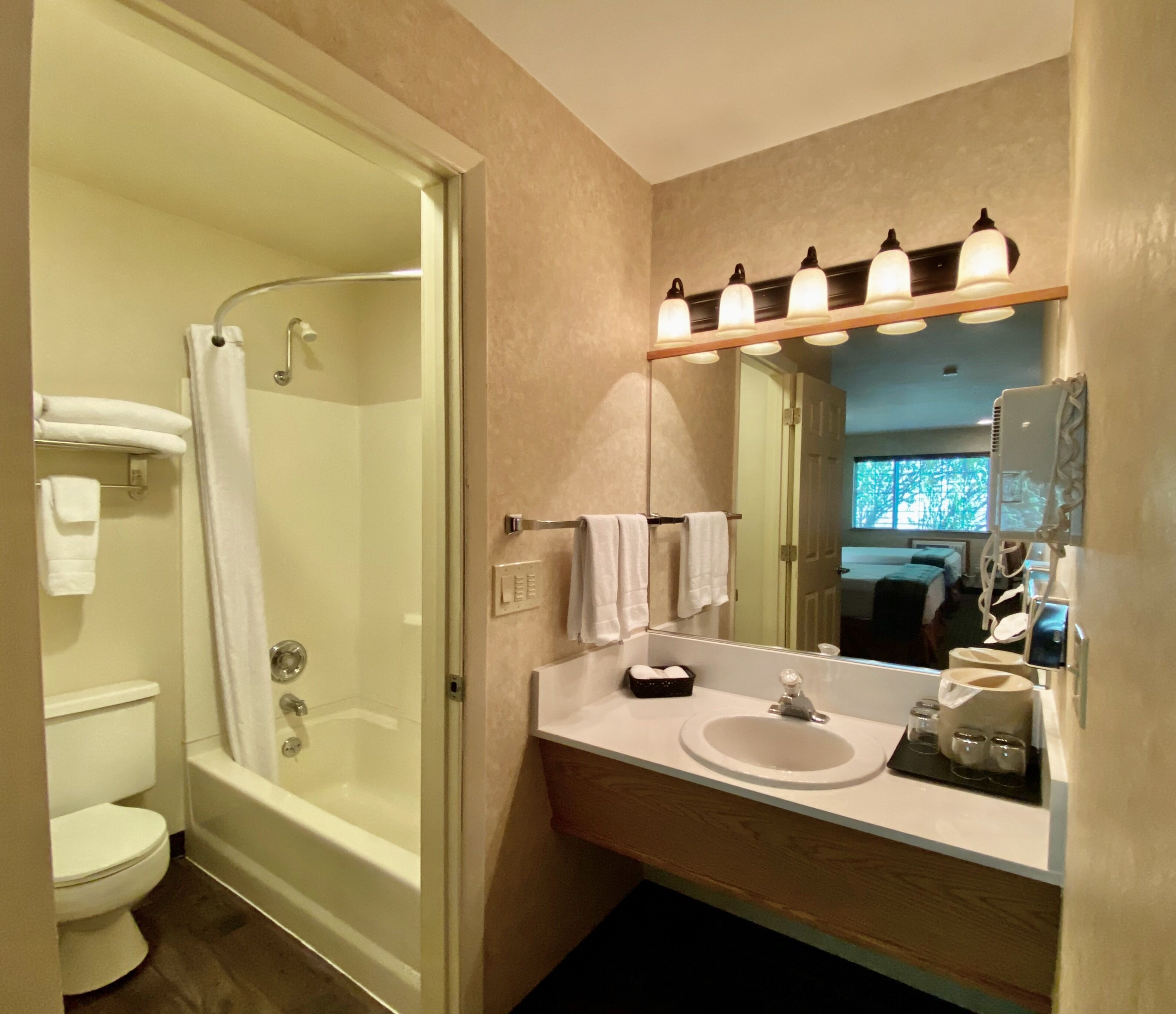 A bathroom with a shower, toilet, sink, and mirror.