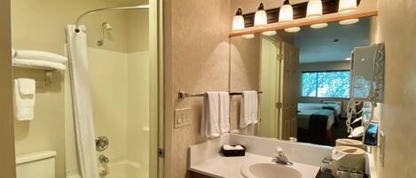 A bathroom with a shower, toilet, sink, and mirror.