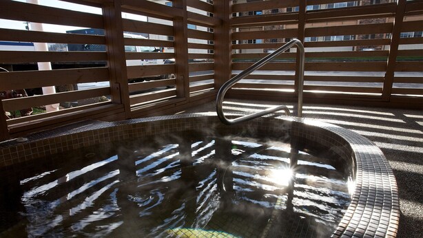 A hot tub with a metal ladder, surrounded by wooden slats and tiled flooring. - Cousins Country Inn (The Dalles)