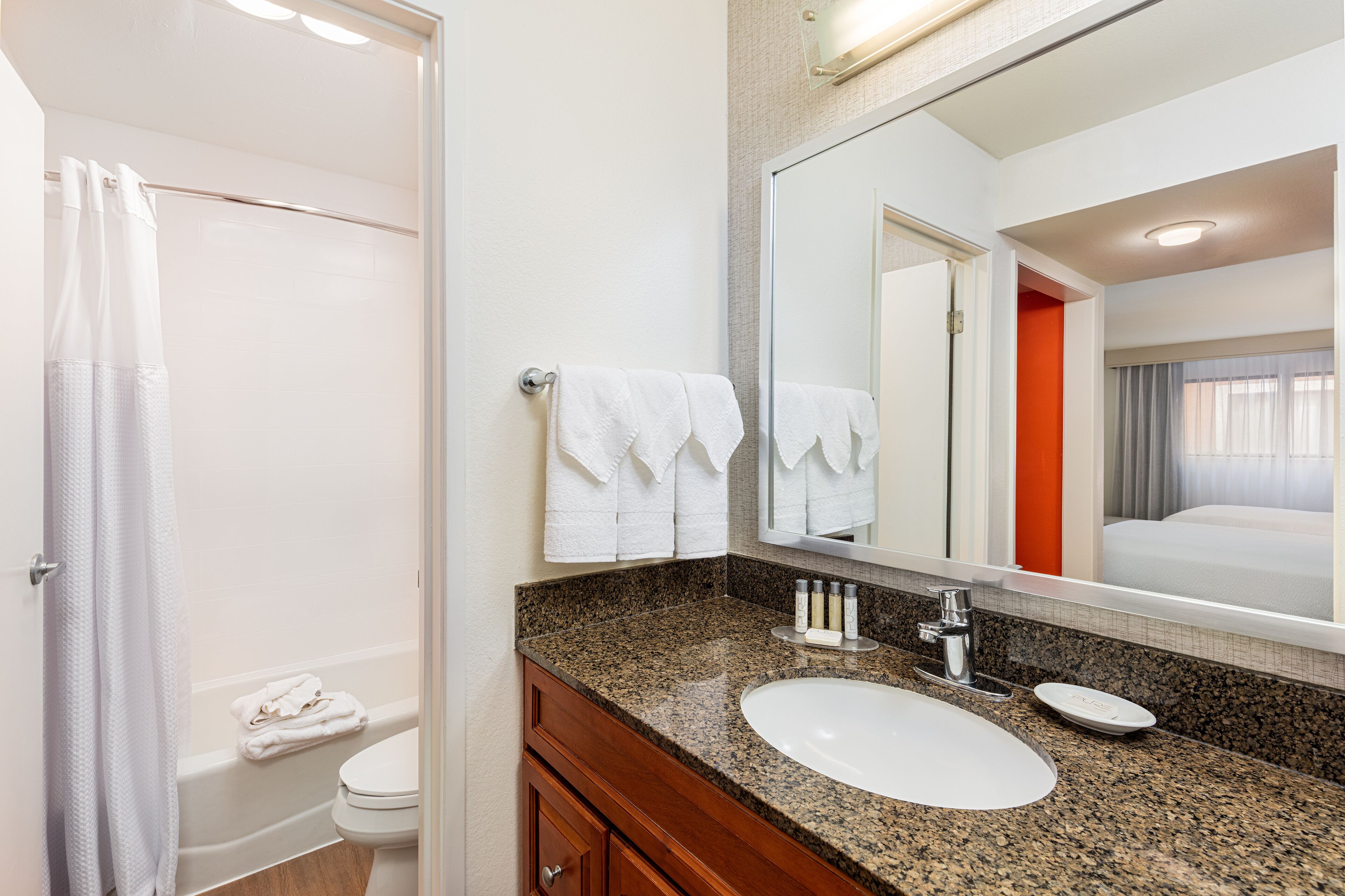 A bathroom with a sink, mirror, and towel rack.