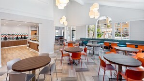A spacious indoor area with multiple seating arrangements, including round tables and chairs, and a counter area with a patterned wall. - Clementine Hotel & Suites Anaheim (Anaheim)