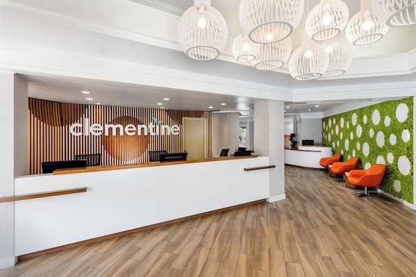 A reception area with a wooden slat wall, a reception desk, and a green wall with circular patterns.