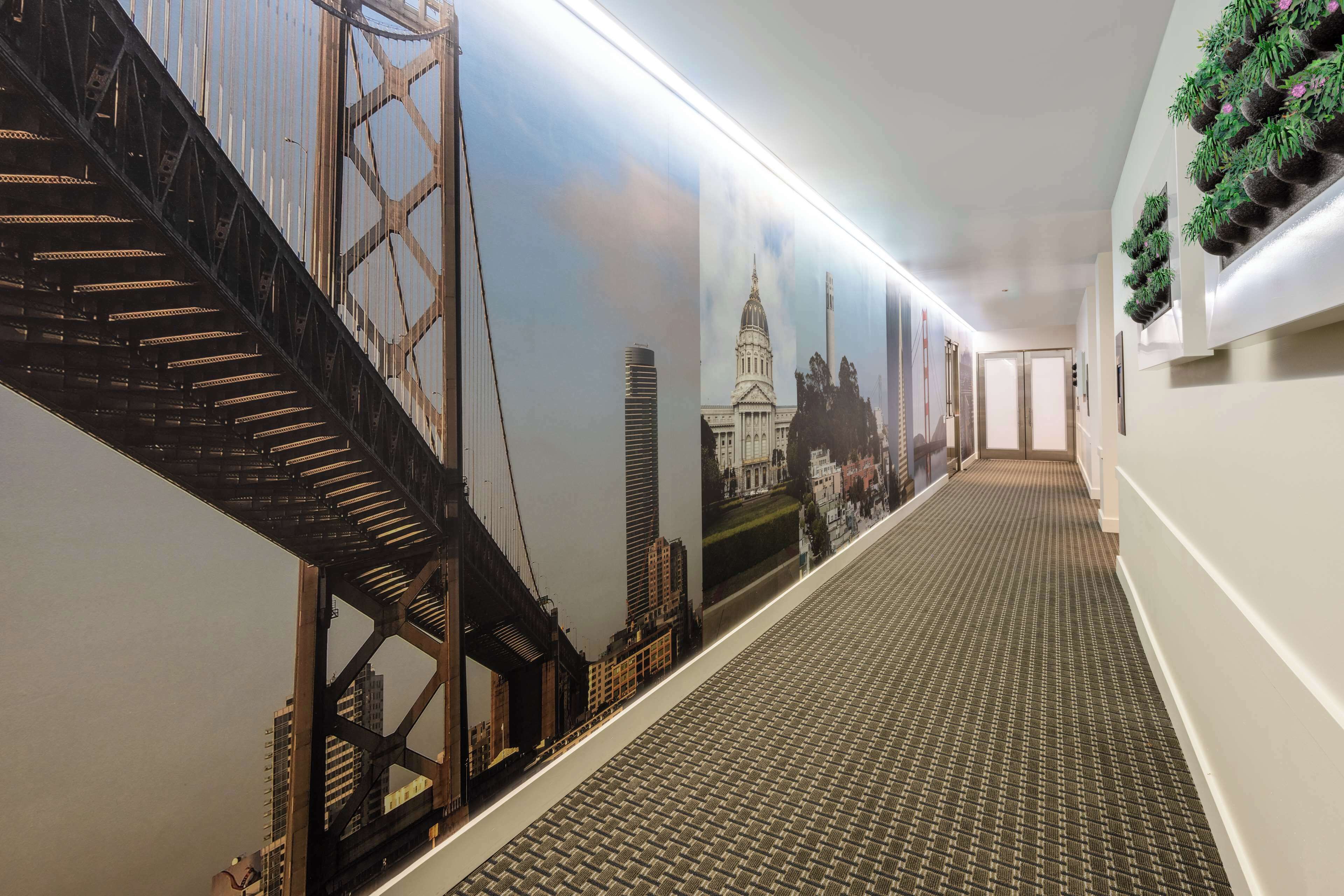 A hallway with a patterned carpet, a large mural of a bridge, and a staircase.