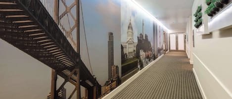 Un pasillo con alfombra estampada, un mural grande de un puente y una escalera.