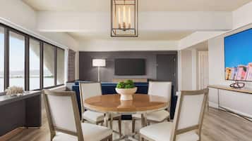 Un comedor moderno con una mesa redonda de madera, sillas blancas acolchadas, una planta en maceta en el centro y una lámpara colgante.