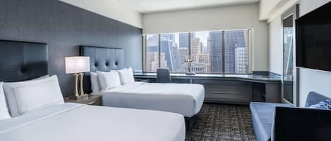 A hotel room with two beds, a large window with a city view, a desk, and a TV.