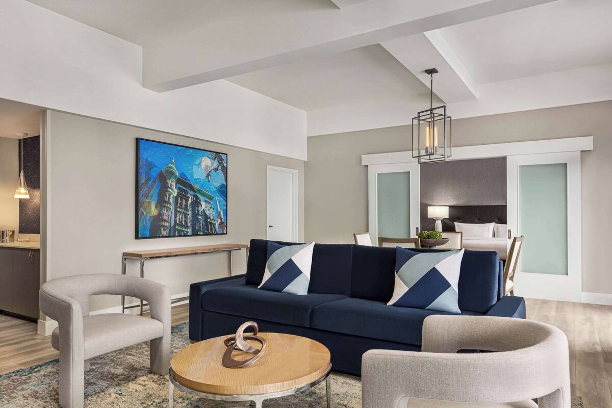 A modern living room with a sofa, armchairs, a round coffee table, and a painting on the wall.