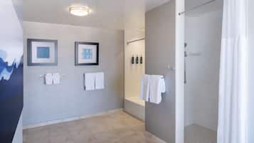 A modern bathroom with a shower, bathtub, and toilet. There are framed pictures on the wall, a towel rack, and a ceiling light.