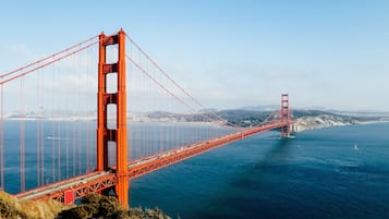A large suspension bridge spanning a body of water with a cityscape in the background.