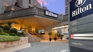 Der Eingang eines Hilton Hotels mit einem Schild, das Parkplätze für die Öffentlichkeit rund um die Uhr und eine FLITE Kaffeebar mit Wein bietet.