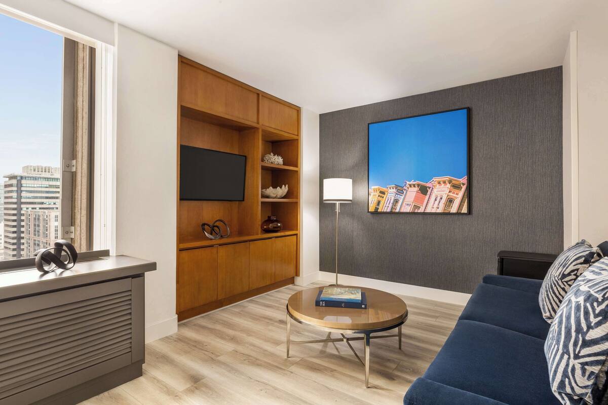 A modern living room with a sofa, a coffee table, a TV, and a bookshelf.