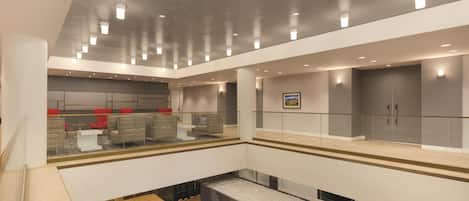 A multi-level indoor space with seating areas, a glass railing, and a framed picture on the wall.