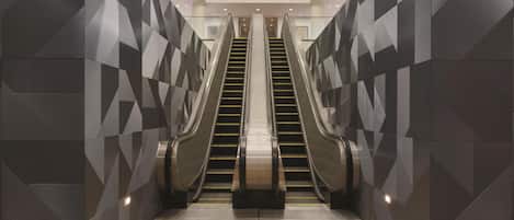 Un ascensor moderno con diseños geométricos en las paredes y suelo de madera.