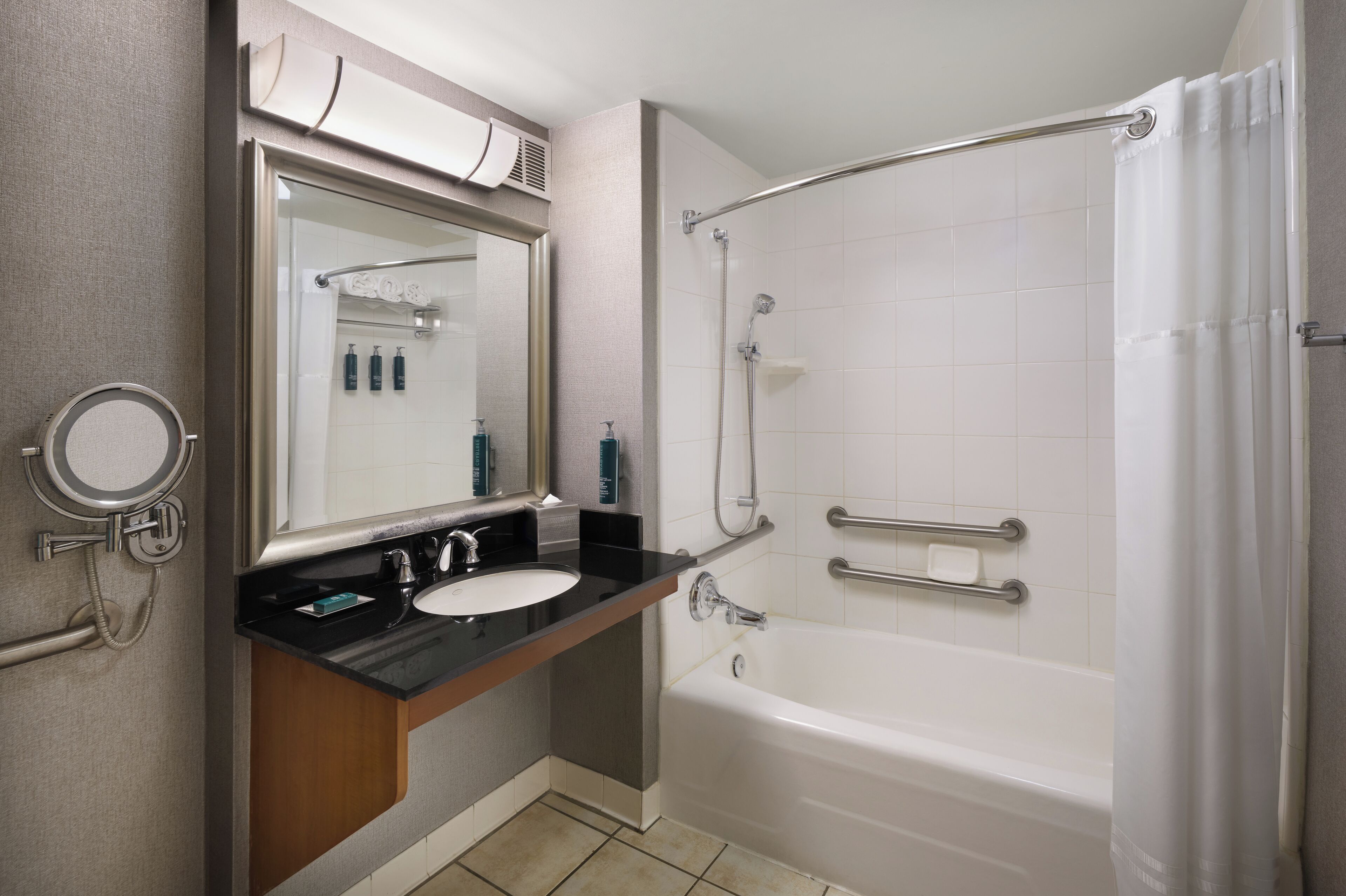 A modern bathroom with a black countertop sink, a large mirror, a white bathtub, and a glass-enclosed shower area.