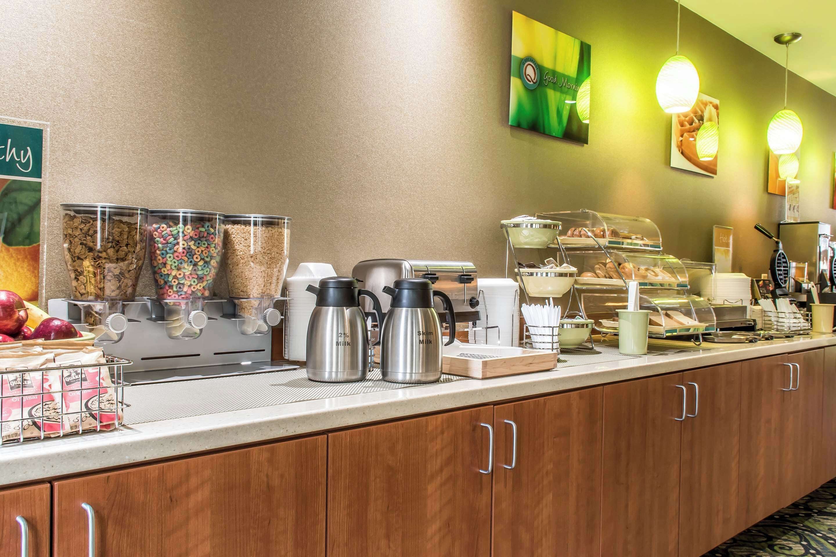 Ein Hotel-Frühstücksbuffet mit verschiedenen Speisen, Kaffeeautomaten und einer Obstschale.