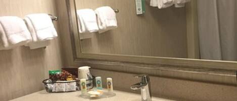 A hotel bathroom with a sink, mirror, towel rack, and toiletries.