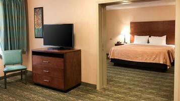 Una habitación de hotel con una televisión sobre un aparador de madera, una cama con cabecero y una silla.