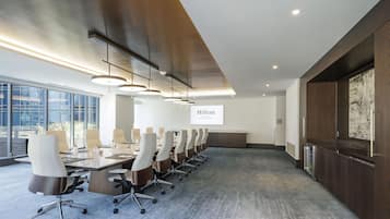 A modern conference room with a long table, chairs, and a projector screen displaying 'Hilton Arlington Rosslyn The Key'.