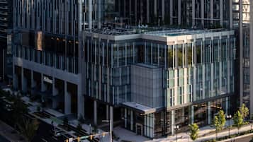 Un edificio moderno con facciata in vetro, ingresso ben visibile e vista sulla strada con semafori.