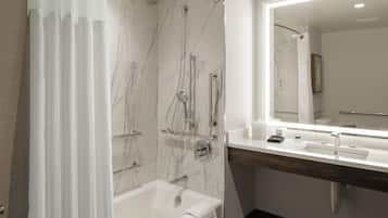 A modern bathroom with a marble shower, a bathtub, and a vanity with a mirror.
