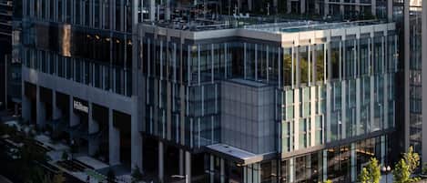 A modern building with a glass facade, a visible entrance, and a street view with traffic lights.