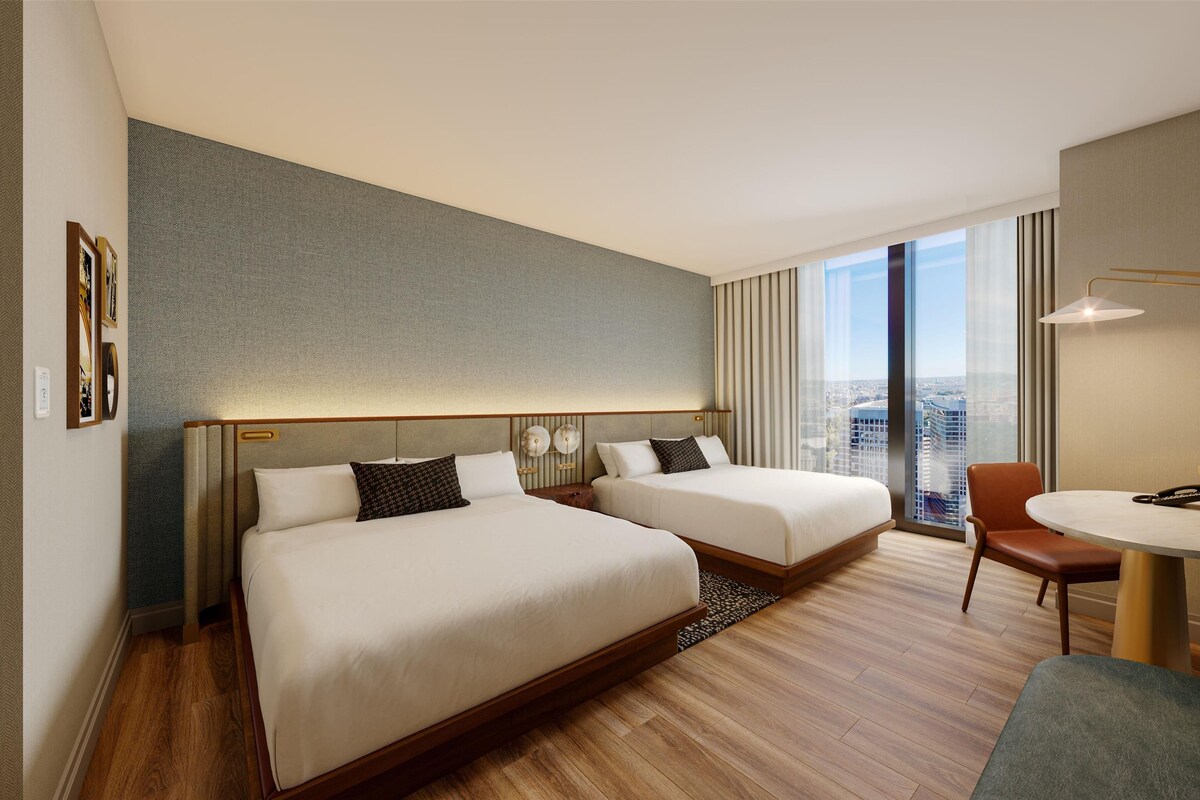 Habitación de hotel con dos camas, un escritorio y una silla.
