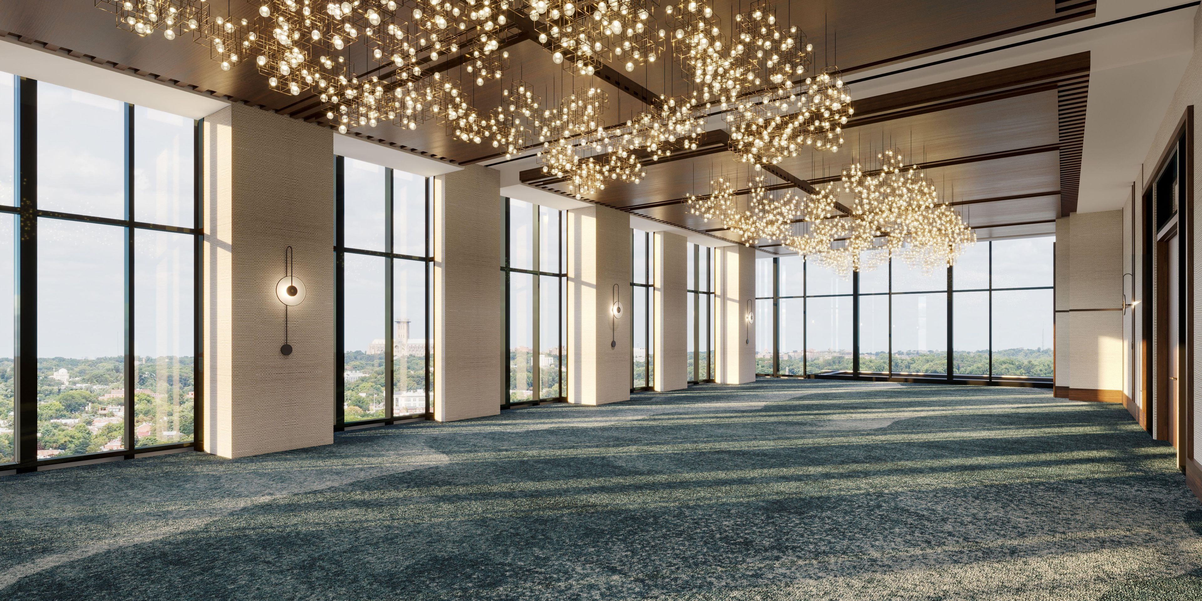 Un salón de conferencias amplio con ventanas grandes, alfombra estampada y un candelabro moderno.