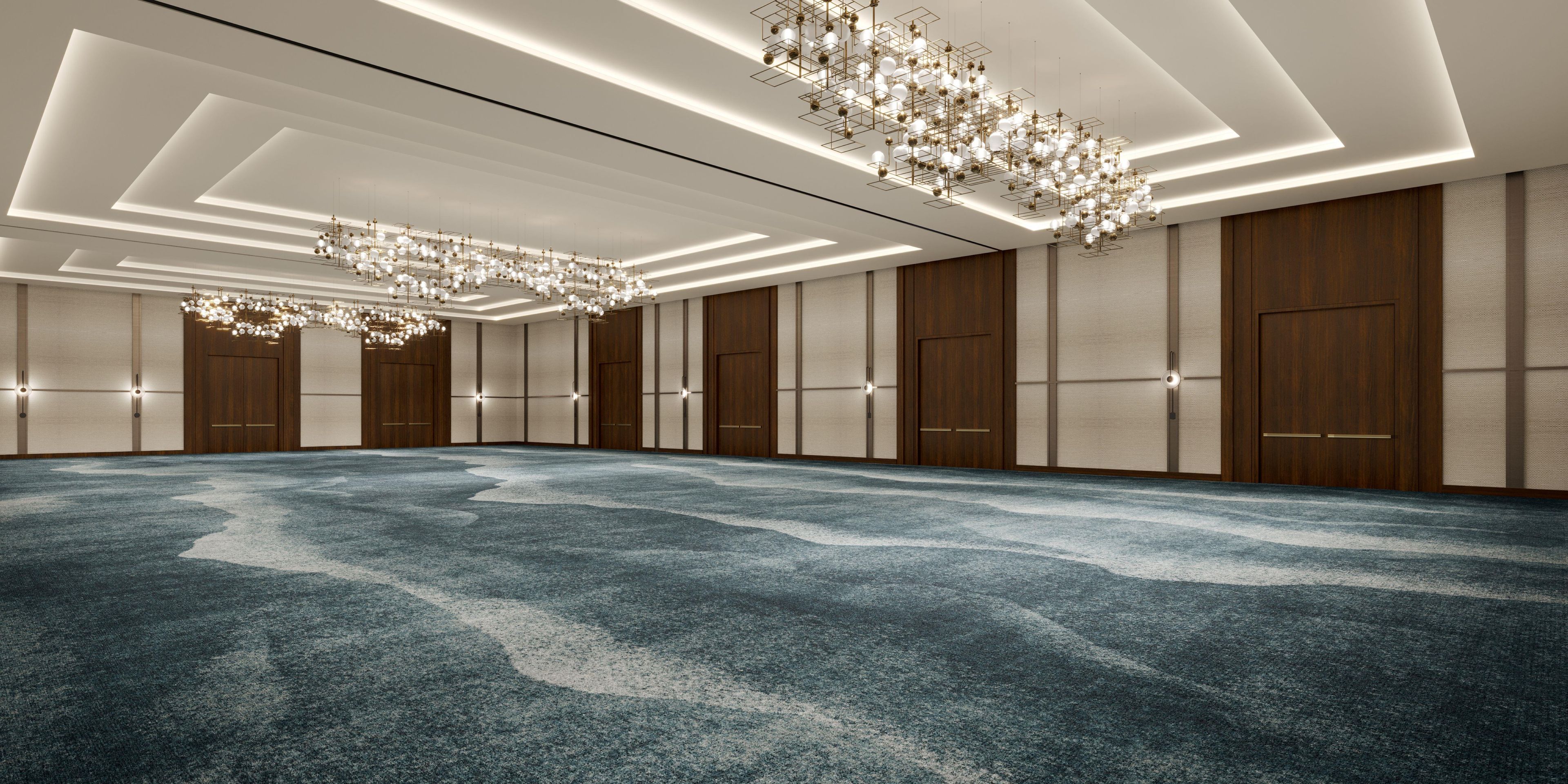 A spacious hotel room with a large carpeted area, multiple doors, and modern chandeliers.