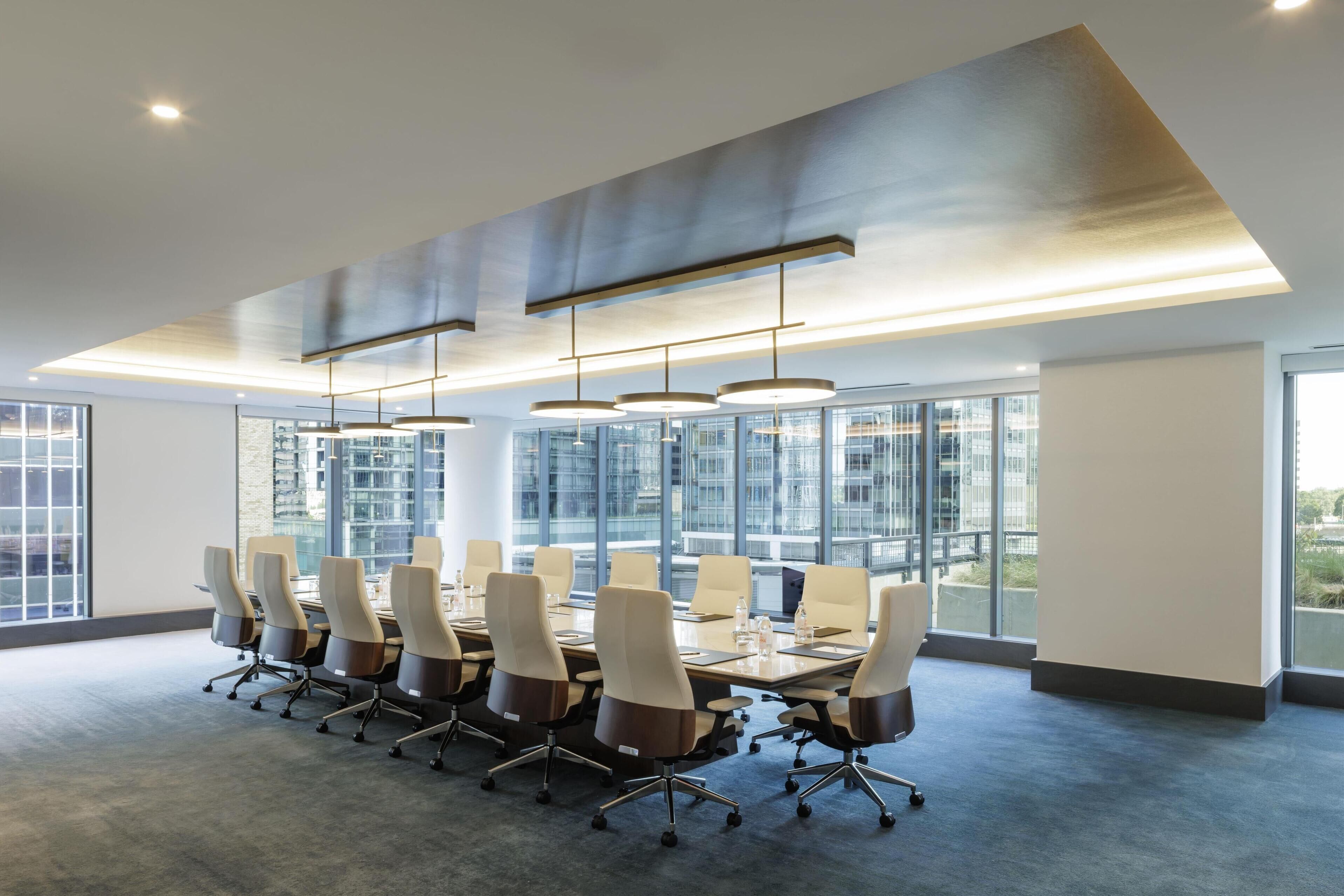 A modern conference room with a long table, multiple chairs, and large windows offering a city view.